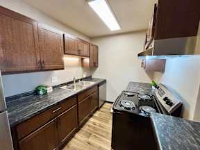 A kitchen with dark wood cabinets and a black counter top.
