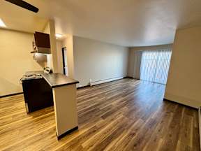 A room with wooden flooring and a desk with a computer on it.
