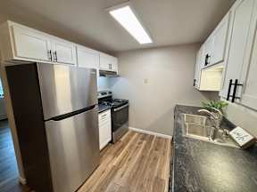 A kitchen with a black counter top and stainless steel appliances.