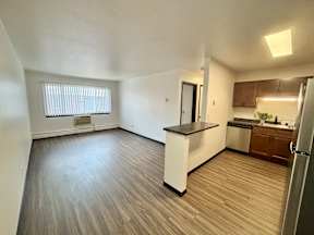 A kitchen with a refrigerator, sink, and cabinets.