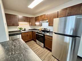 A kitchen with a stainless steel refrigerator and wooden cabinets.