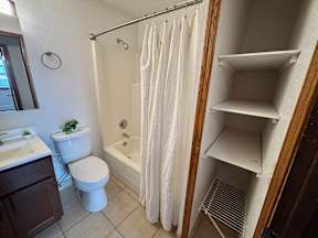 A white bathroom with a toilet, sink, and shower.