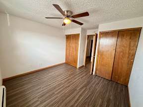 A room with a ceiling fan and wooden flooring.