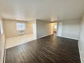 A room with wooden flooring and a window with blinds.
