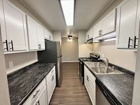 A kitchen with black countertops and white cabinets.