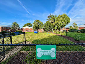 A sign that says "Welcome to Our Dog Park" is in front of a fence.