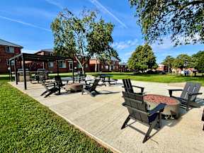 A sunny day at a park with a fire pit and chairs.