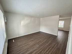 A room with wooden flooring and white walls.