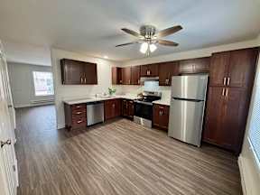 A kitchen with wooden cabinets and a stainless steel refrigerator.