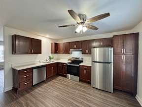 A kitchen with a stainless steel refrigerator and wooden cabinets.