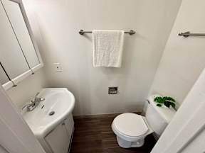 A white toilet sits next to a white sink in a small bathroom.