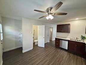 A room with a ceiling fan and a kitchen area with a sink and dishwasher.