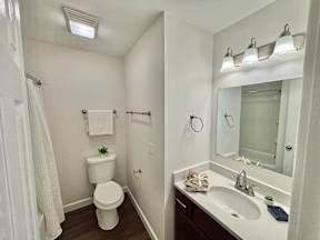 A white toilet is in a small bathroom with a sink and mirror.