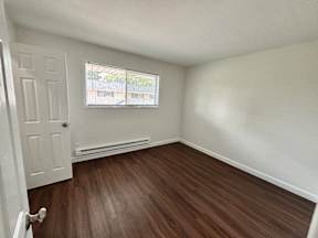 A room with a white door and a window with a view of a building outside.