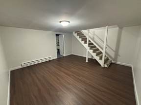 A room with a staircase and wooden flooring.