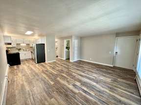 A room with a kitchen area and a dining table.