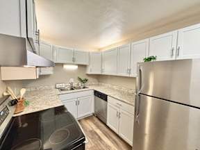 A kitchen with a black stove top oven and a stainless steel refrigerator.
