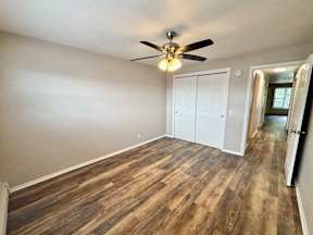 A room with a ceiling fan and wood flooring.