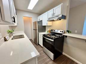 A modern kitchen with a stove, sink, and refrigerator.