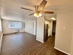 A room with a ceiling fan and wooden flooring.
