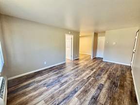 A room with wooden flooring and white walls.