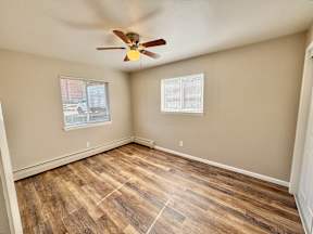 A room with a ceiling fan and wooden flooring.