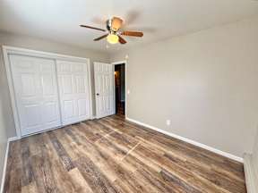 A room with a ceiling fan and wooden flooring.