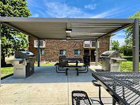 A covered outdoor area with a grill and picnic table.