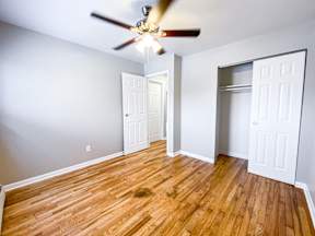 A room with a ceiling fan and wooden flooring.