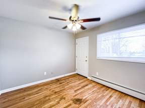A room with a ceiling fan and wooden flooring.