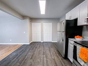 A kitchen with a refrigerator, oven, and cabinets.