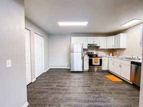 A kitchen with a refrigerator, oven, and sink.