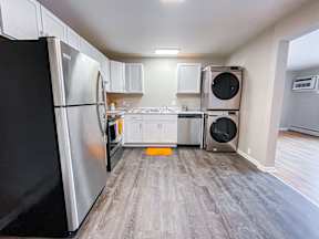 A kitchen with a black refrigerator and a stainless steel oven.