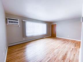 A room with wooden flooring and a window with blinds.