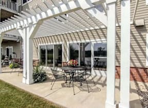 A patio with a table and chairs under a white pergola.