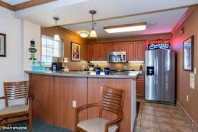 A kitchen with wooden cabinets and a countertop with two chairs.