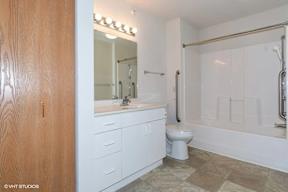 A white bathroom with a wooden door and a tiled floor.