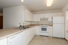 A white kitchen with a sink, stove, and refrigerator.