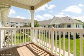 A white porch with a view of apartment buildings.