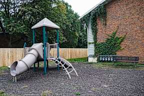 A playground with a slide and a wooden fence.