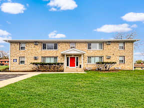 A brick building with a red door and windows.