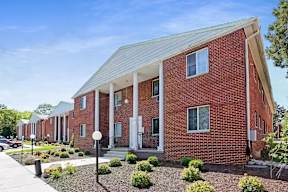 A red brick building with a white roof and a front porch.
