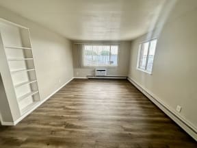 an empty living room with wood flooring and a window