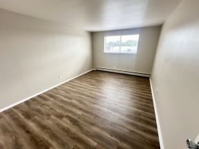 an empty room with wood flooring and a window