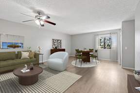 Oversized living area in Oro apartment home with wood-style plank flooring and a ceiling fan over dining nook.