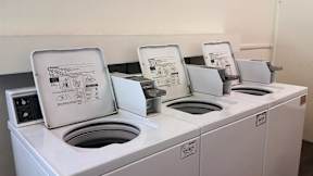 Three white washing machines with instruction manuals on top.