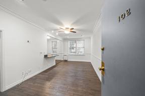 Spacious living area in charming 6128 Wilshire apartment home with gorgeous wood flooring, white walls, an open concept layout leading to dining and kitchen area
