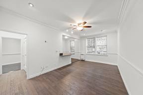 Spacious living area in charming 6128 Wilshire apartment home with gorgeous wood flooring, white walls, an open concept layout leading to dining and kitchen area