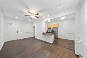 Spacious living area in charming 6128 Wilshire apartment home with gorgeous wood flooring, white walls, an open concept layout leading to dining and kitchen area