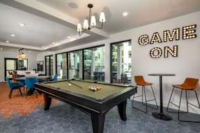 A pool table with a sign that says "Game On" behind it.